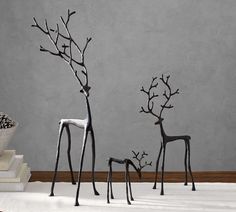 three metal deer sculptures sitting on top of a white floor next to a pile of books