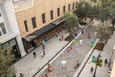 an overhead view of people walking and sitting on benches in the middle of a courtyard