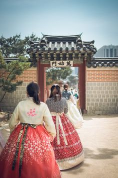 two women in traditional chinese dress walking towards an archway