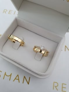 two gold wedding rings sitting in a box