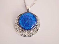 This beautiful silver metal star pendant with dichroic blue glass center is definitely and eye catcher! The dichroic glass is a special type of glass which can show different colors depending on the angle it is viewed at. The blue color looks like a glistening night sky. The Silver tone pendant is accentuated with cut out stars giving this necklace a truly celestial feel to it Pendant is 2 inches long Chain is 20 inches and is steel If you love celestial or Victorian jewelry or just looking for