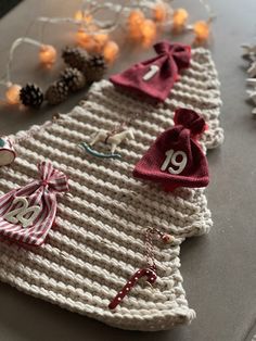 a knitted christmas tree decoration with numbers and ornaments on the table next to it