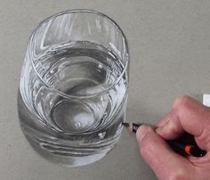 a person is drawing a glass with pencils