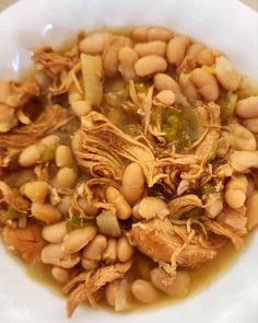 a white bowl filled with beans and meat