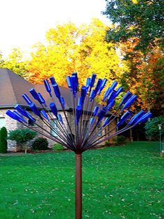 a blue vase sitting on top of a metal pole in front of a green yard