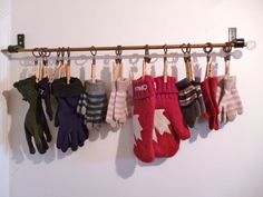 several pairs of mitts hanging from a rack on a wall with gloves attached to it