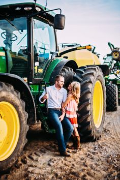 a man and woman sitting in front of a tractor