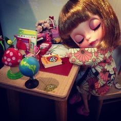 a doll is sitting at a desk with toys on the table and around her head