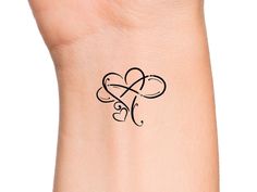 a woman's wrist with a heart tattoo on the left side of her arm