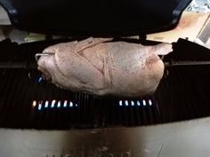 a raw chicken is being cooked on the grill in an oven with it's lid open