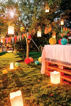 an outdoor party with lanterns and paper lanterns on the grass, in front of a picnic table