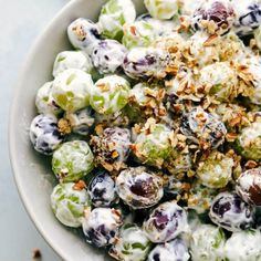 a white bowl filled with fruit salad next to grapes