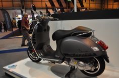 a motor scooter is on display in a showroom with people walking around