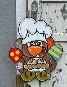 a turkey with a chef's hat and mittens on its head hanging from a door