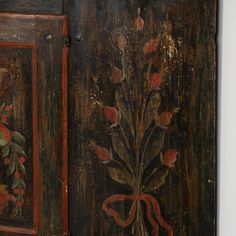 an old wooden cabinet with flowers painted on the doors and bow tie around the handles