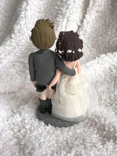 a small figurine of two people sitting next to each other on a white blanket