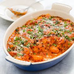 a casserole dish with meat, cheese and parsley in it on a table