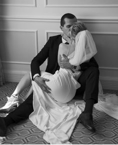 a man in a tuxedo and woman in a dress sitting on the floor