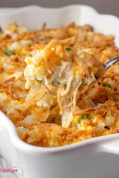 a spoon full of macaroni and cheese being lifted from a casserole dish