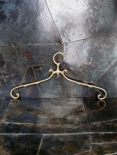 a metal hanger on the ground in front of a tiled wall