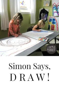 two children are sitting at a table with artwork on it and the words simon says, draw