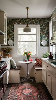 a kitchen with white cabinets and floral wallpaper on the walls, along with a round dining table