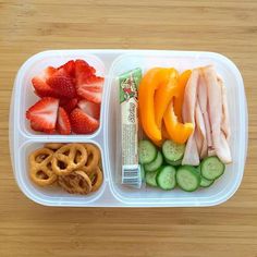 a plastic container filled with fruit, vegetables and pretzels