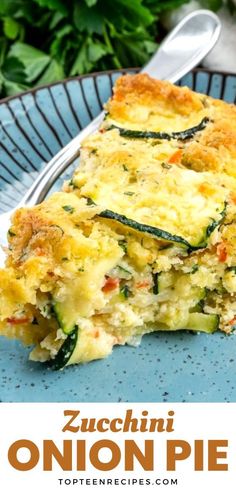 zucchini onion pie on a blue plate with a fork and green plants in the background