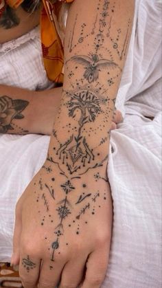 a woman's arm with tattoos on it and her hand in the air,