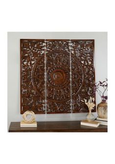 an intricately carved wooden panel on a shelf with vases and flowers in the foreground