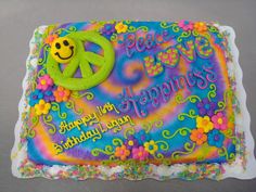 a birthday cake with a peace sign and flowers on the bottom is decorated in rainbow colors