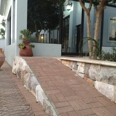 two large vases sitting on the side of a building next to some trees and bushes