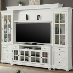 a white entertainment center with glass doors and drawers in a living room next to a gray wall