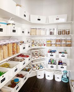 an organized pantry with white bins filled with food and containers full of cereal on the shelves