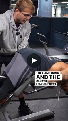 a man is working on his leg muscles in the gym while another man looks at him