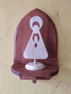 a wooden clock mounted to the side of a wall with a carved design on it