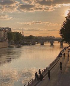 people are walking along the river bank in paris