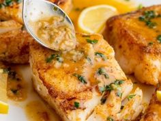 a close up of some fish on a plate with lemon wedges and parsley