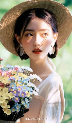 a woman wearing a straw hat holding a bouquet of flowers