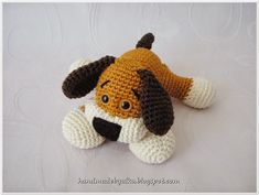 a crocheted stuffed dog laying on top of a white surface