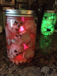 two mason jars filled with halloween decorations on top of a granite counter next to a green and red light