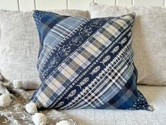 a blue and white plaid pillow sitting on top of a bed next to a blanket