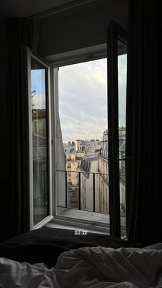 an open window looking out onto the city from a room in a building with a balcony