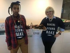 two people standing in front of a counter with some food on it and one holding a plate