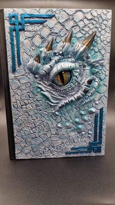 a close up of a dragon's eye on a piece of paper with blue paint