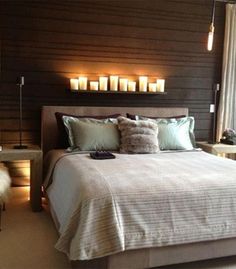 a large bed sitting next to a window with candles on the headboard and night stands