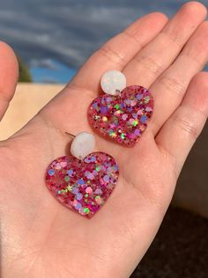 Each pair of sparkly heart earrings are handmade to order, therefore no two pairs are identical! Every piece will be slightly one of a kind and unique. However, I try to get as close to the photos as possible :) Made with non-toxic stainless steel stud pads.  Heart width is approximately 1.25", and is made with epoxy resin, iridescent pink heart confetti and pink chunky mix glitter with stars 🌟 The circle stud portion is white with holographic glitter!  Hypoallergenic and nickel-free. Thanks fo Glittery Jewelry, Heart Confetti, Steel Accessories, Stainless Steel Accessories, Glitter Earrings, Girly Gifts, Circle Studs, Holographic Glitter, Accessories Unique