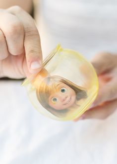 a woman holding a small round object with a child's face on it