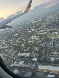 an airplane wing flying over a city at dusk