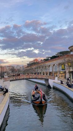 two boats are traveling down the river in front of buildings and people sitting on benches